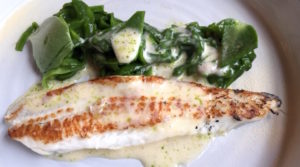 A perfectly cooked filet of flounder with kohl rabi, spinach and parsley and an oyster sauce.